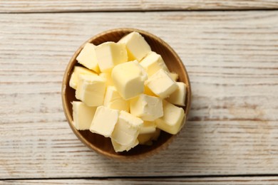 Photo of Tasty butter cubes in bowl on light wooden table, top view