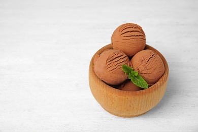 Photo of Wooden bowl of chocolate ice cream on white table, space for text