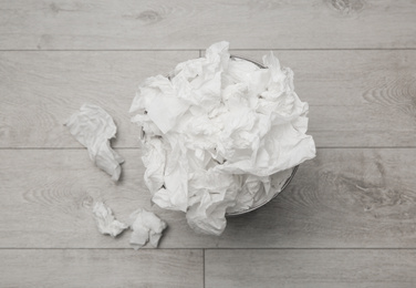 Photo of Used paper tissues and trash can on wooden floor, flat lay