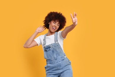 Photo of Happy young woman dancing on orange background