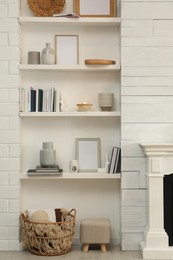 Photo of Books, empty frames and different decor on shelves indoors. Interior design