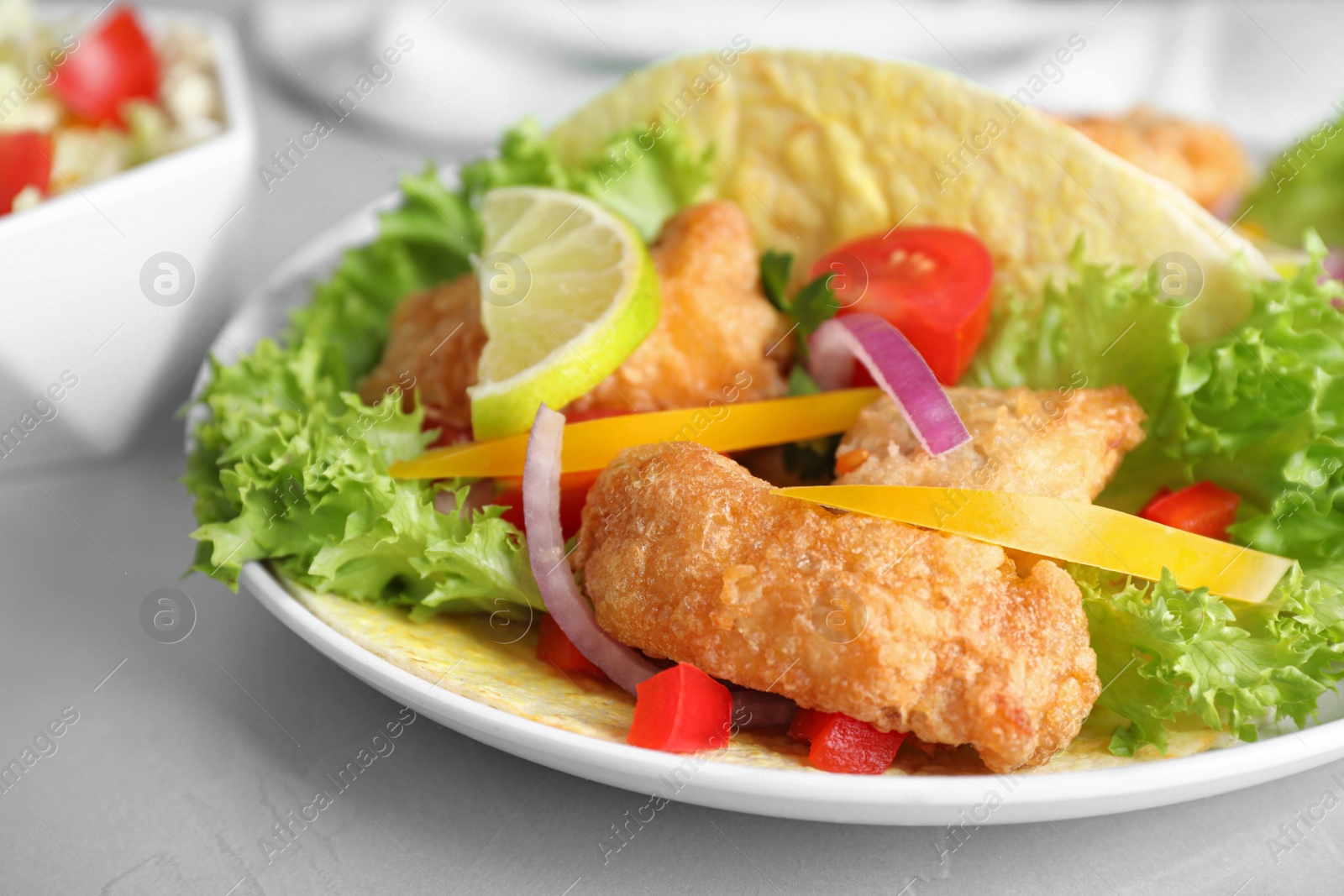 Photo of Delicious fish tacos served on light  grey table, closeup