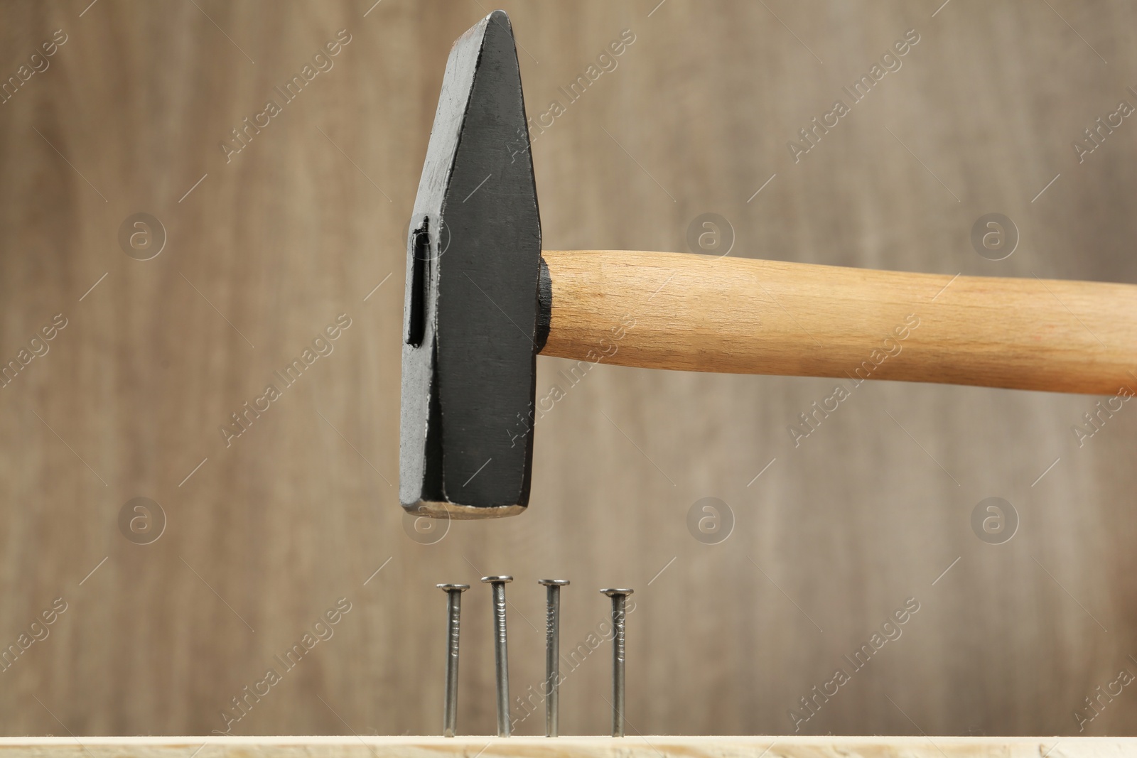 Photo of Hammering nail into plank against wooden background