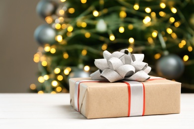 Beautiful gift box and blurred Christmas tree on background