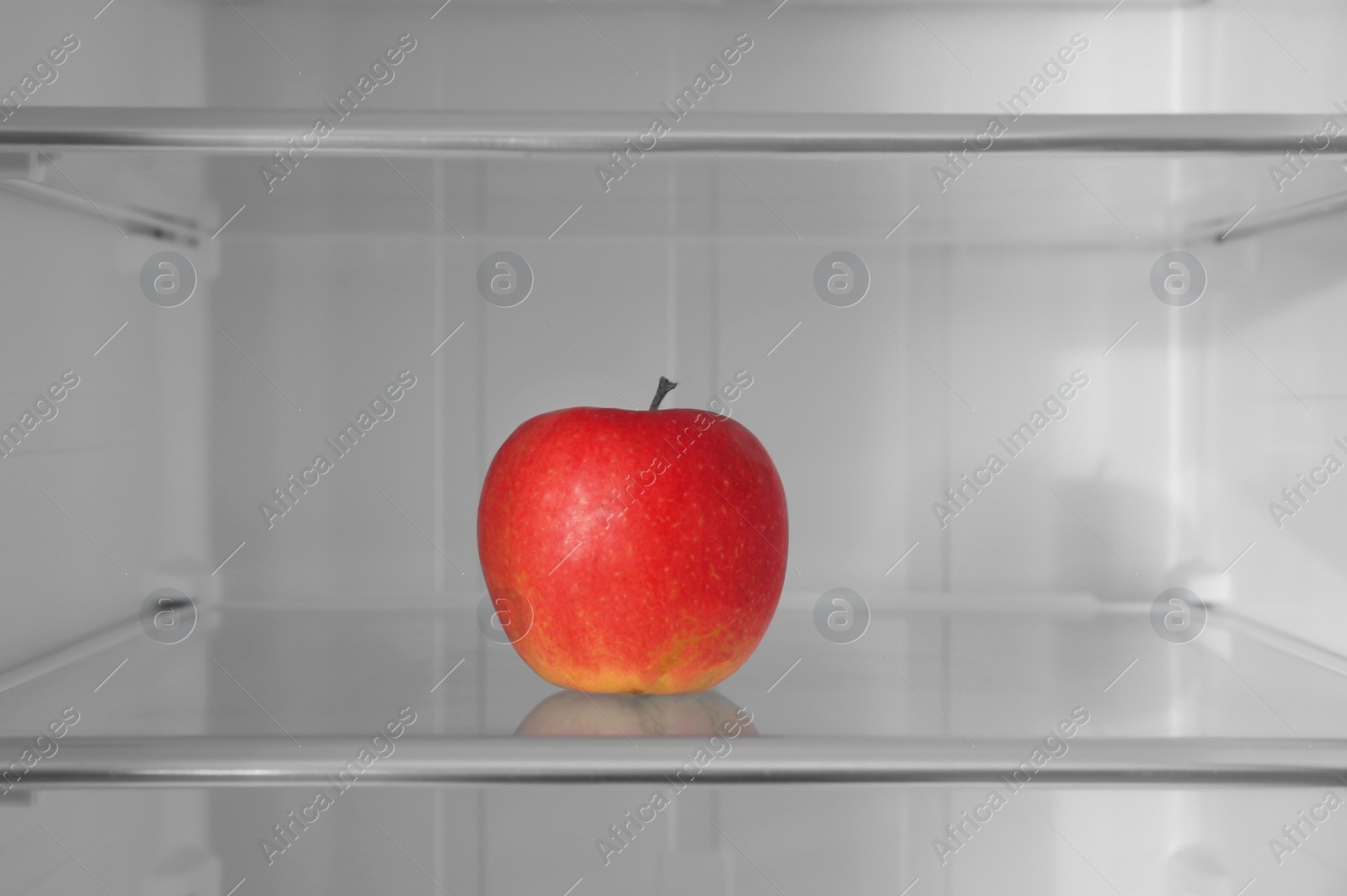 Photo of Red apple on shelf inside modern refrigerator