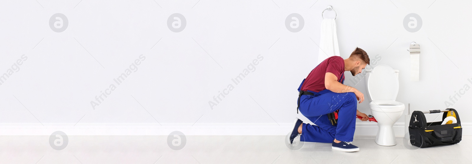 Image of Young man working with toilet bowl in bathroom, space for text. Banner design