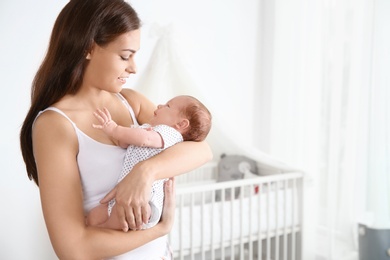 Photo of Young woman with her newborn baby at home. Space for text