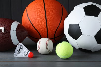 Set of different sport balls and shuttlecock on grey wooden table, closeup