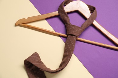 Photo of Hanger with necktie on color background, top view
