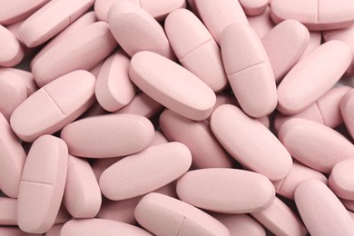 Photo of Pink vitamin capsules as background, top view