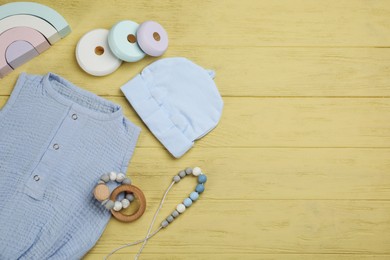 Photo of Flat lay composition with baby clothes and accessories on yellow wooden table. Space for text