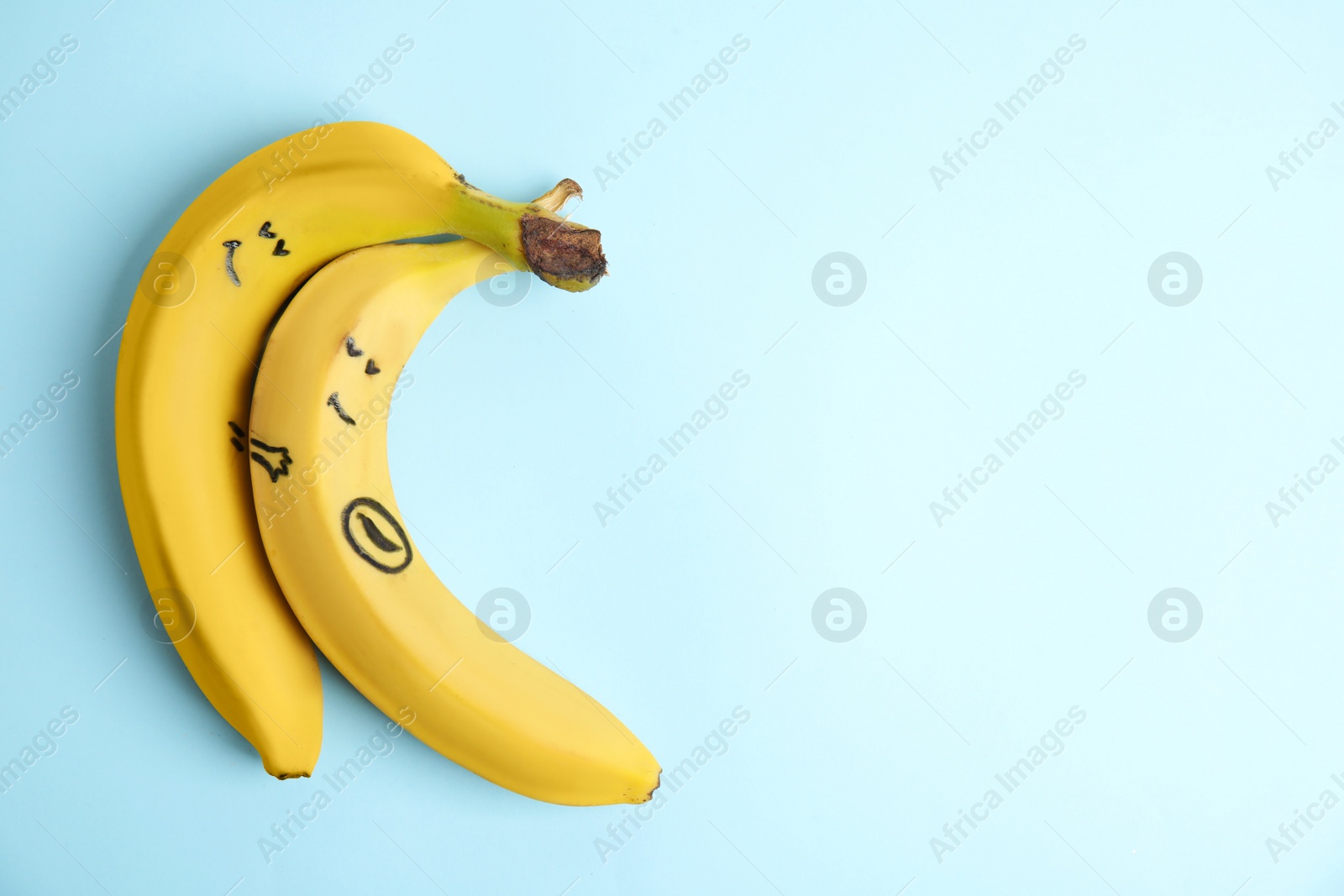 Photo of Bananas as man and his pregnant woman on light blue background, top view. Space for text