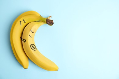 Photo of Bananas as man and his pregnant woman on light blue background, top view. Space for text