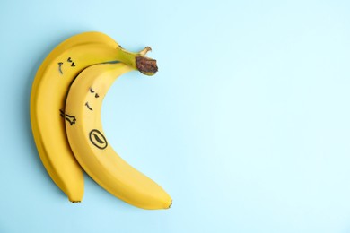 Bananas as man and his pregnant woman on light blue background, top view. Space for text