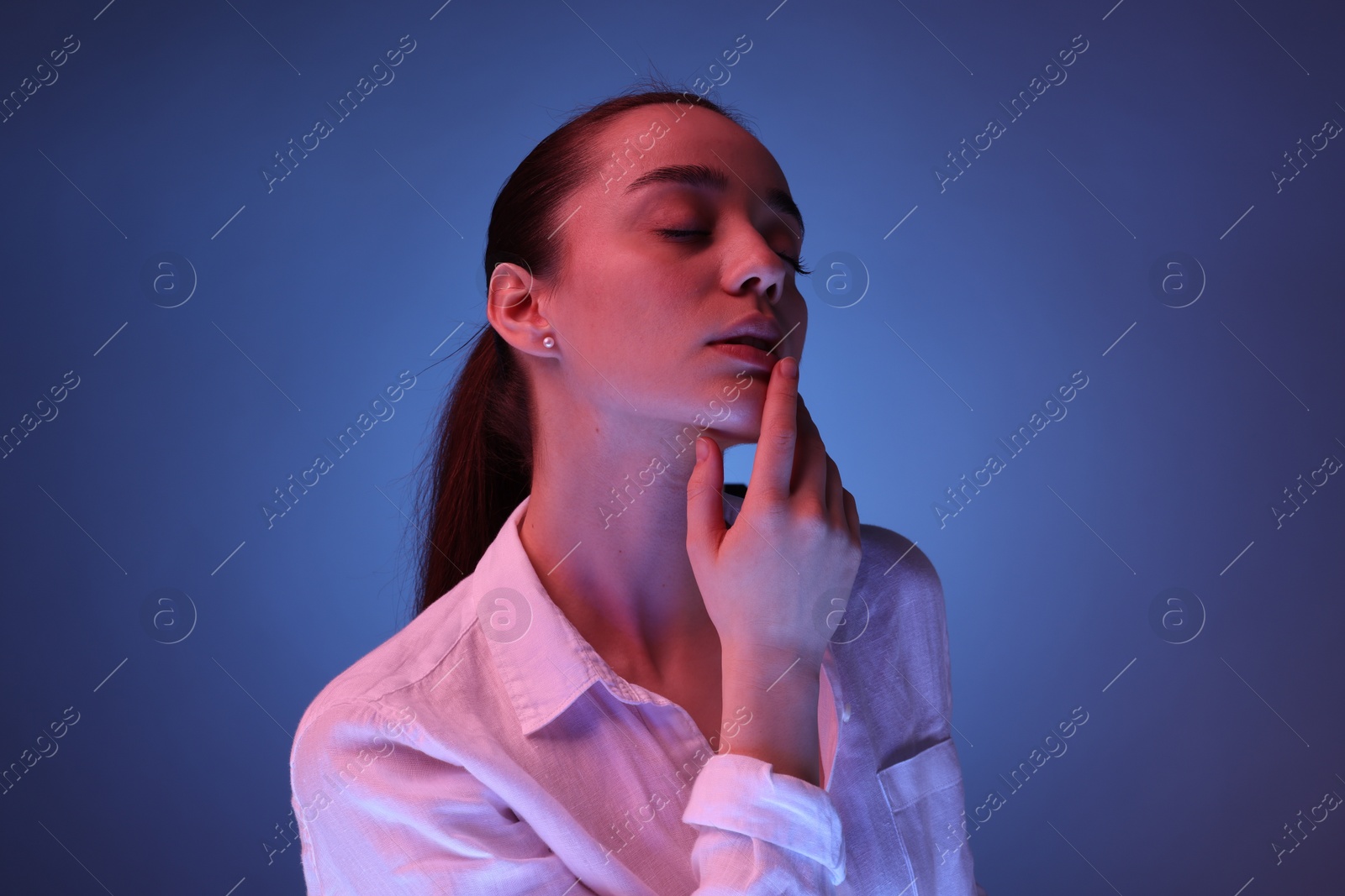 Photo of Portrait of beautiful young woman posing on blue background with neon lights