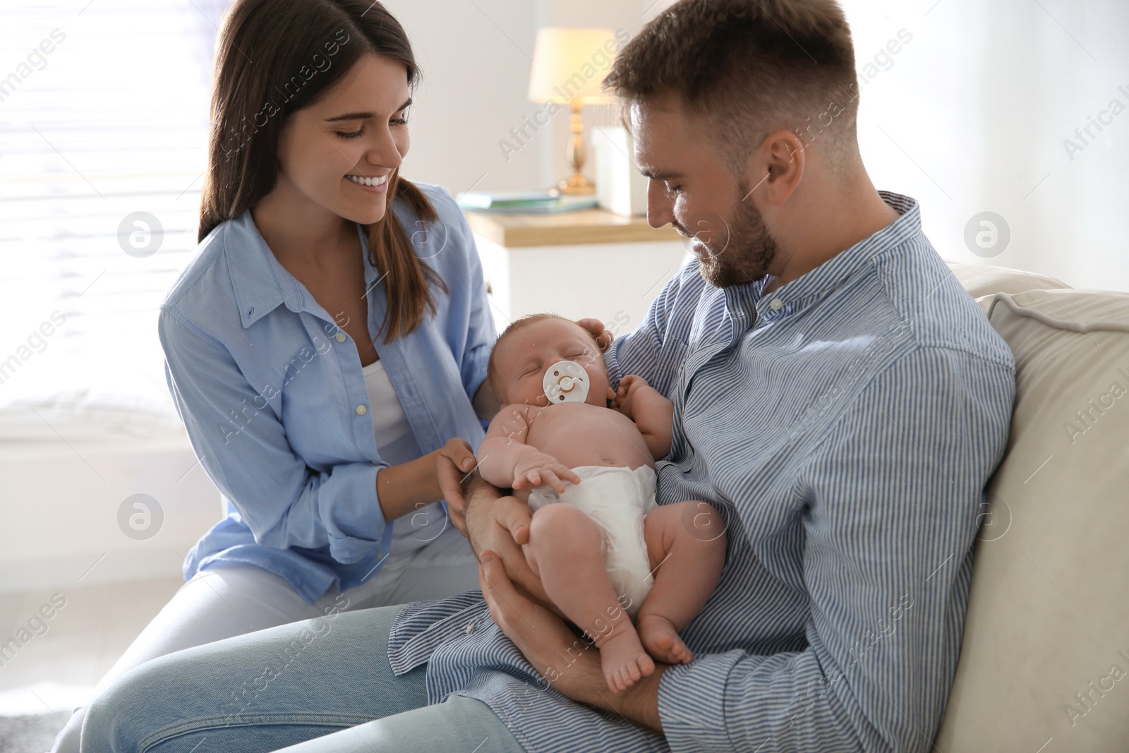 Photo of Happy couple with their newborn baby at home