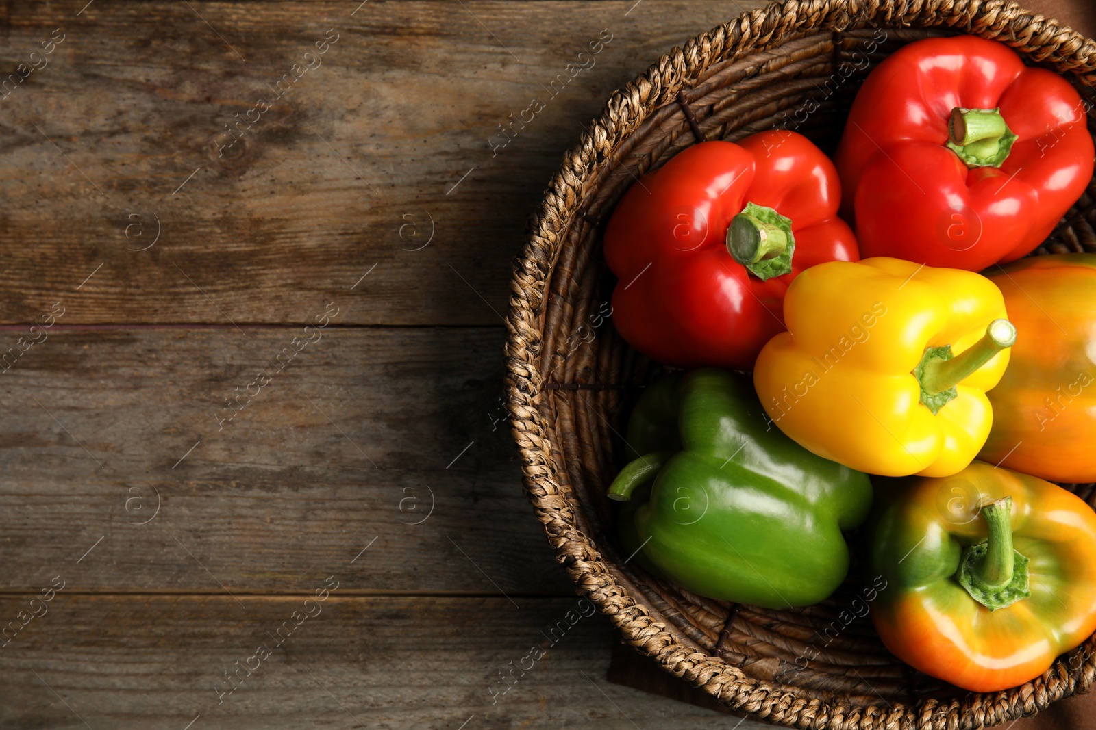 Photo of Bowl with ripe paprika peppers on wooden background, top view