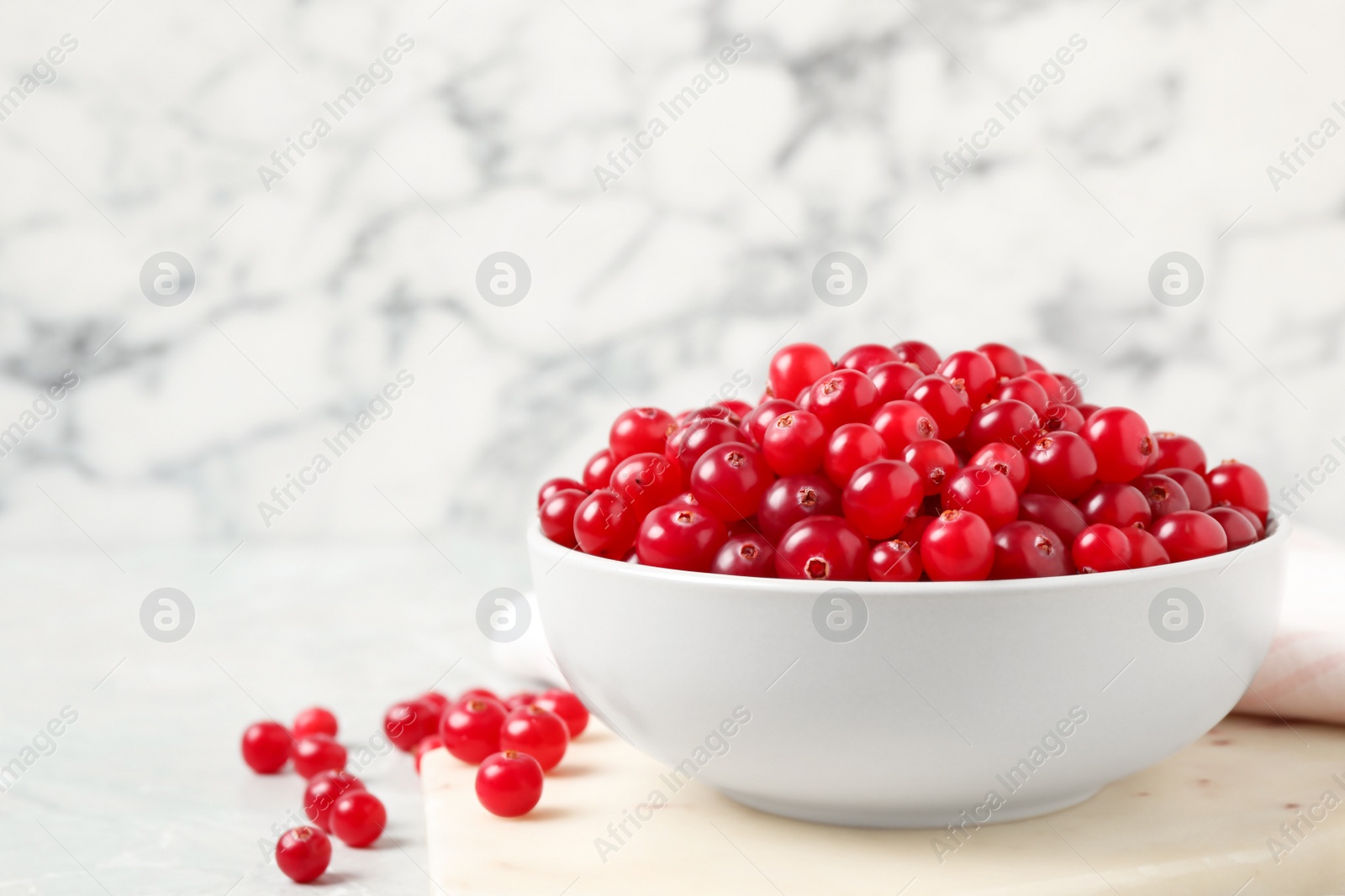 Photo of Bowl with tasty ripe cranberries on table, closeup