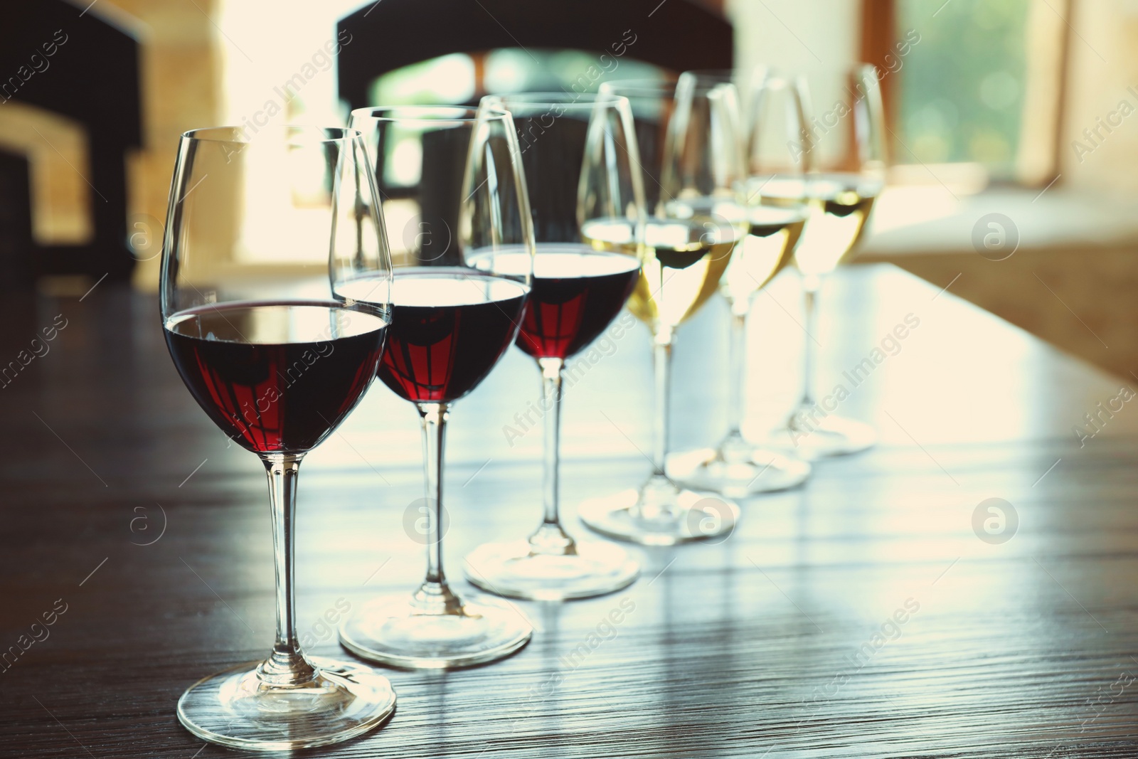 Photo of Glasses of white and red wines on wooden table