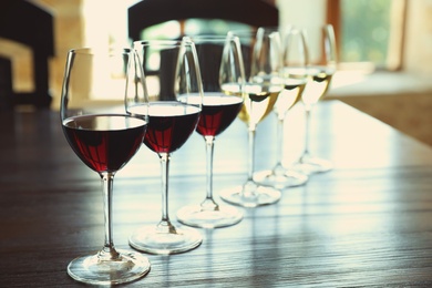 Photo of Glasses of white and red wines on wooden table