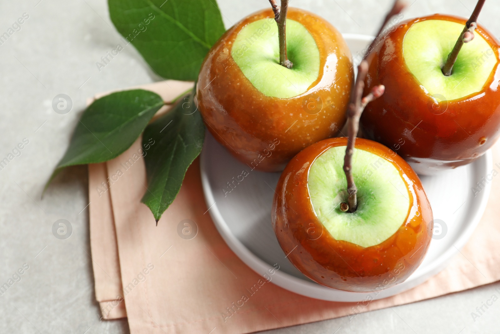 Photo of Plate with delicious green caramel apples on table