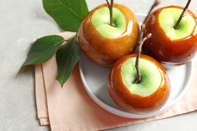 Plate with delicious green caramel apples on table