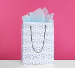 Photo of Gift bag with paper on white table against pink background