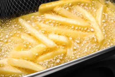 Photo of Cooking delicious french fries in hot oil, closeup