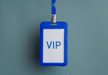 Photo of Blue plastic vip badge hanging on color background