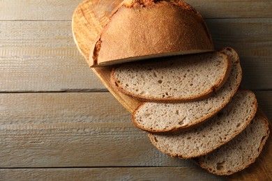 Photo of Freshly baked cut sourdough bread on wooden table, top view. Space for text