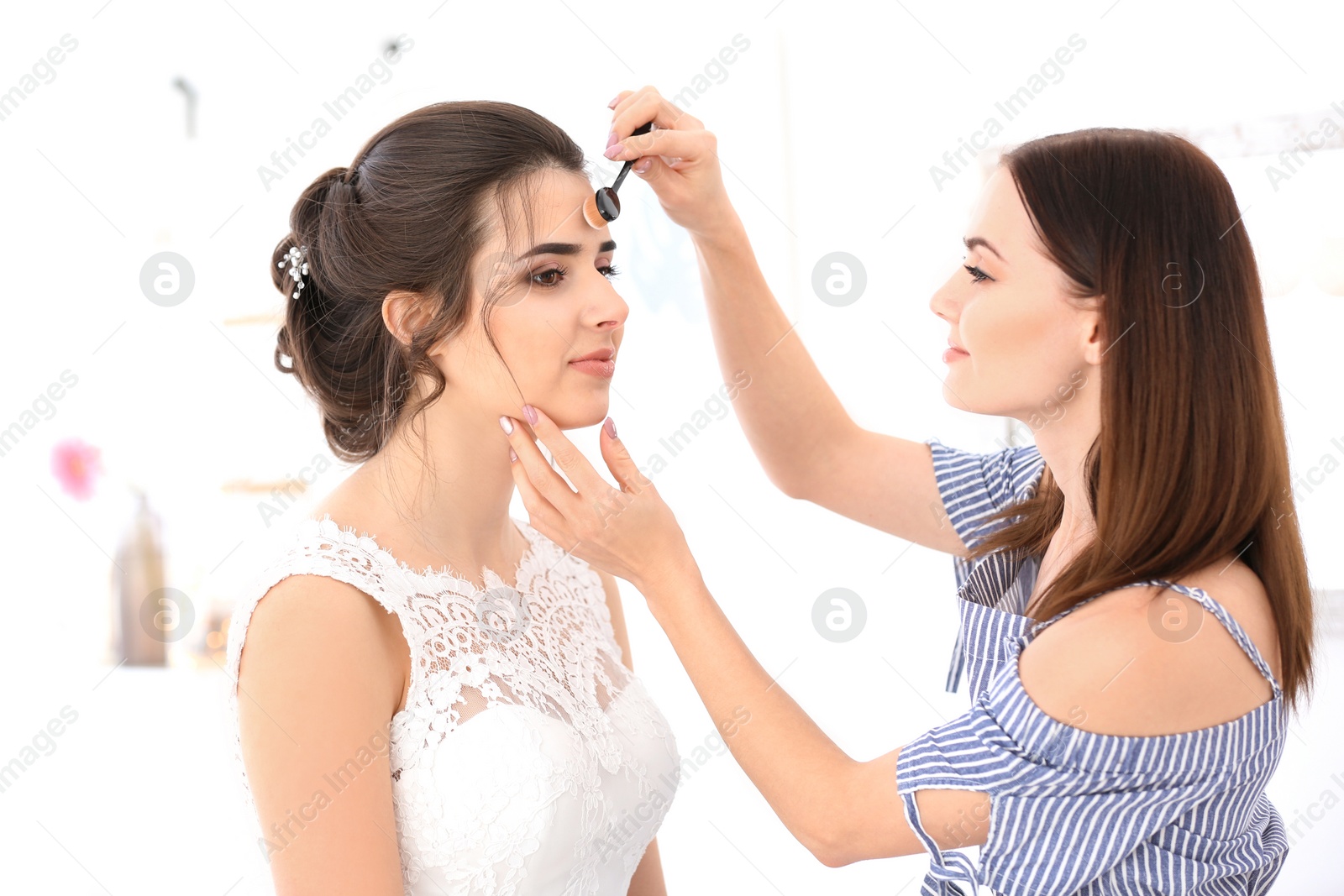 Photo of Professional makeup artist working with young woman in salon