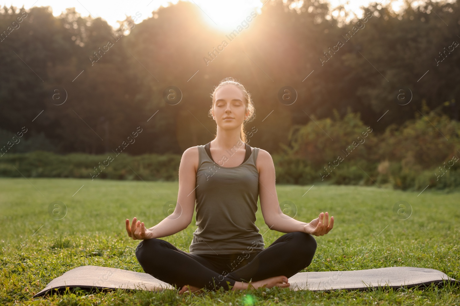 Photo of Beautiful woman practicing yoga outdoors on sunny day. Lotus pose