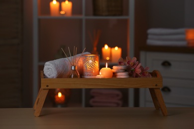 Photo of Composition with candles, flowers and stones on wooden table in spa salon