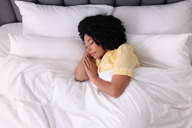 Photo of Beautiful young woman sleeping in soft bed, top view