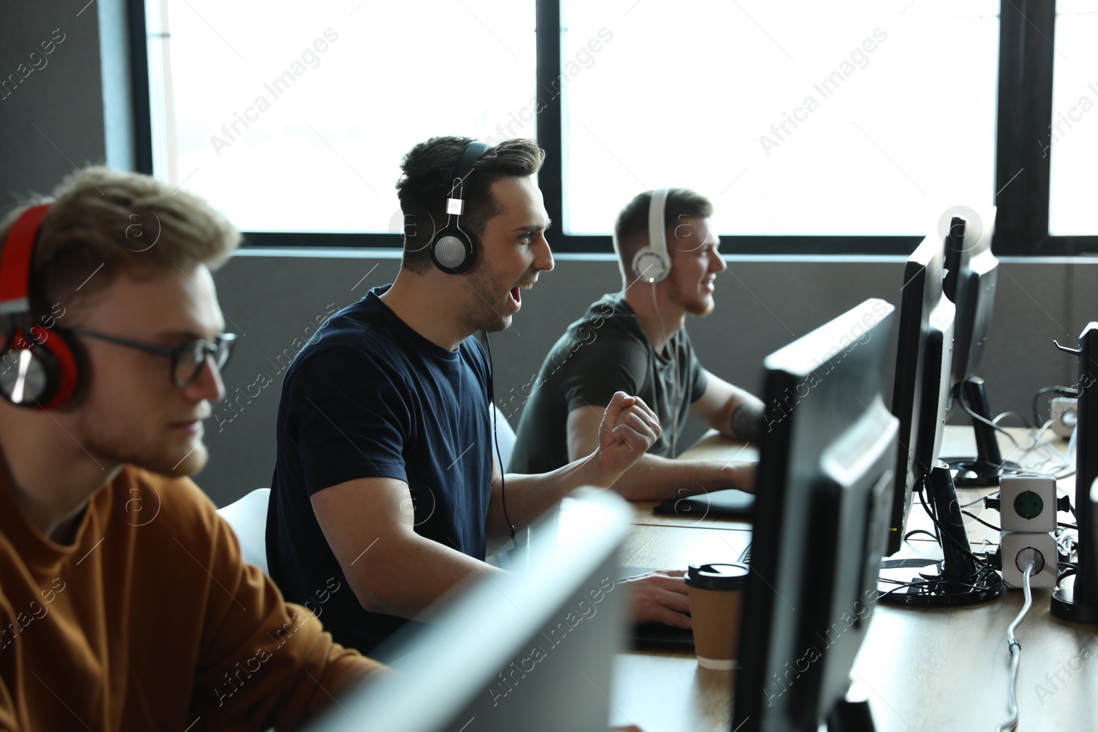 Photo of Men playing video games in internet cafe