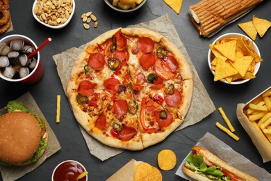 Pizza, burger and other fast food on black table, flat lay