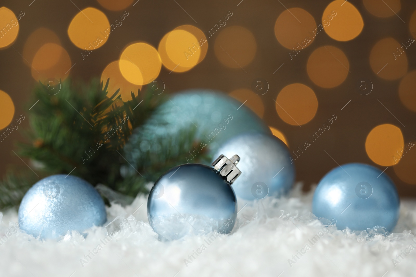 Photo of Beautiful Christmas balls on snow against blurred festive lights. Space for text