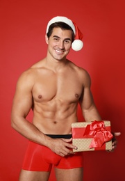 Sexy shirtless Santa Claus with gift on red background