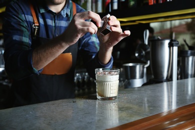 Photo of Barman making White Russian cocktail at counter in pub, closeup. Space for text