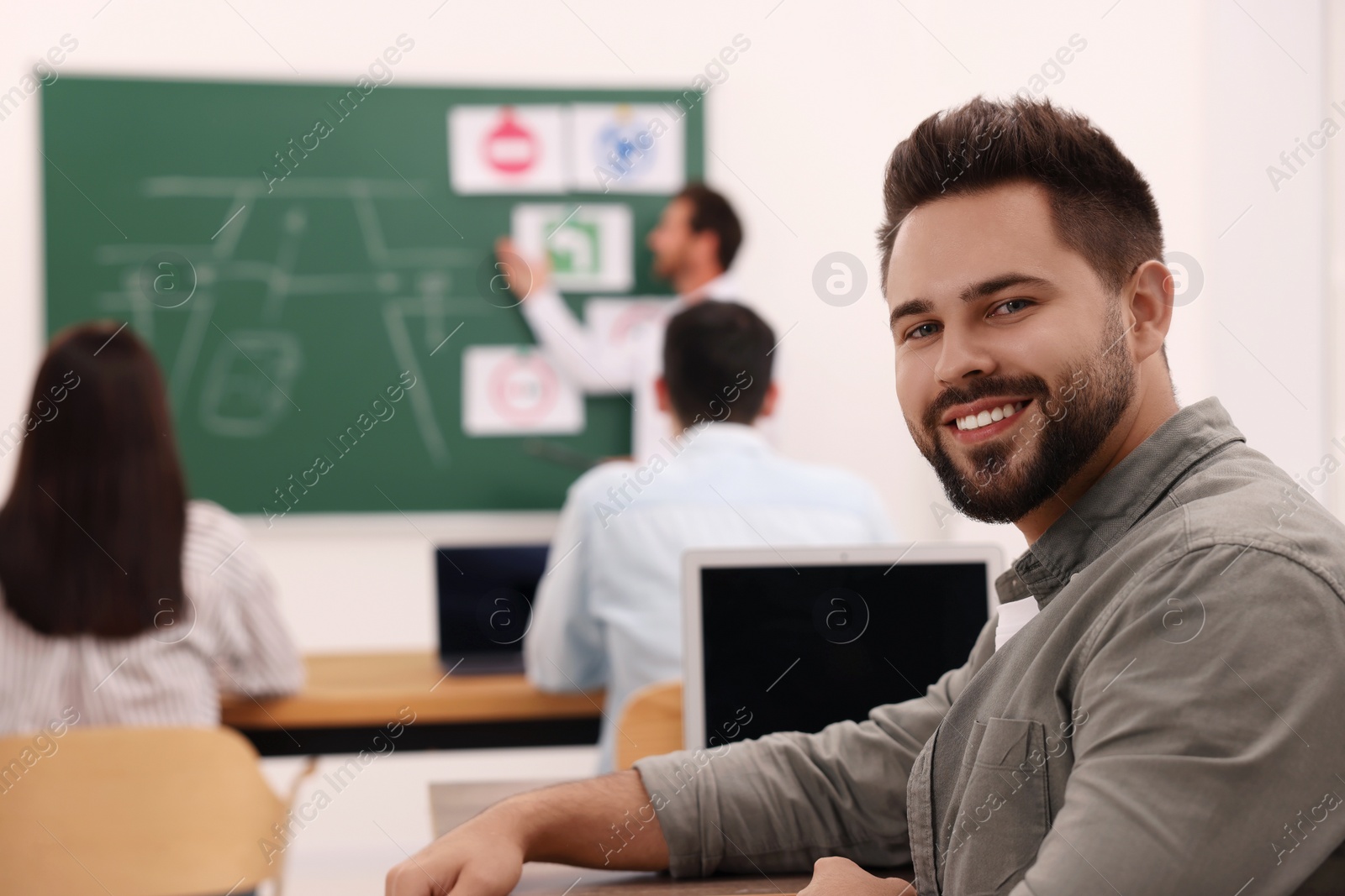 Photo of Happy man at desk in class during lesson in driving school