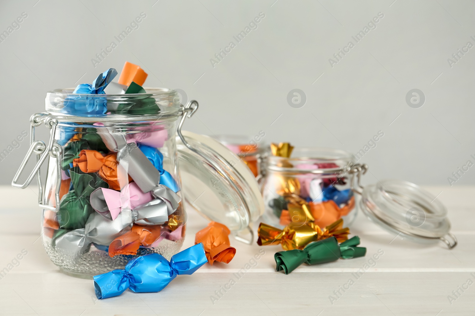 Photo of Candies in colorful wrappers on white wooden table