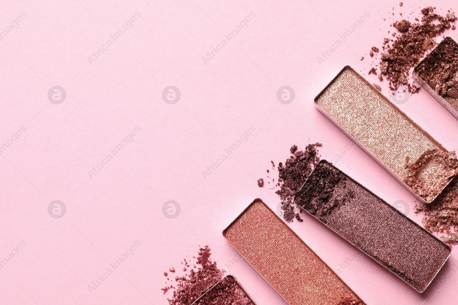 Photo of Different crushed eye shadows on pink background, flat lay. Space for text