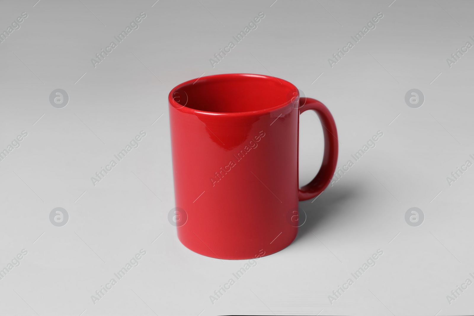 Red ceramic mug on light grey background Photo of Red ceramic mug on light grey background