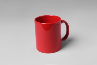 Photo of Red ceramic mug on light grey background