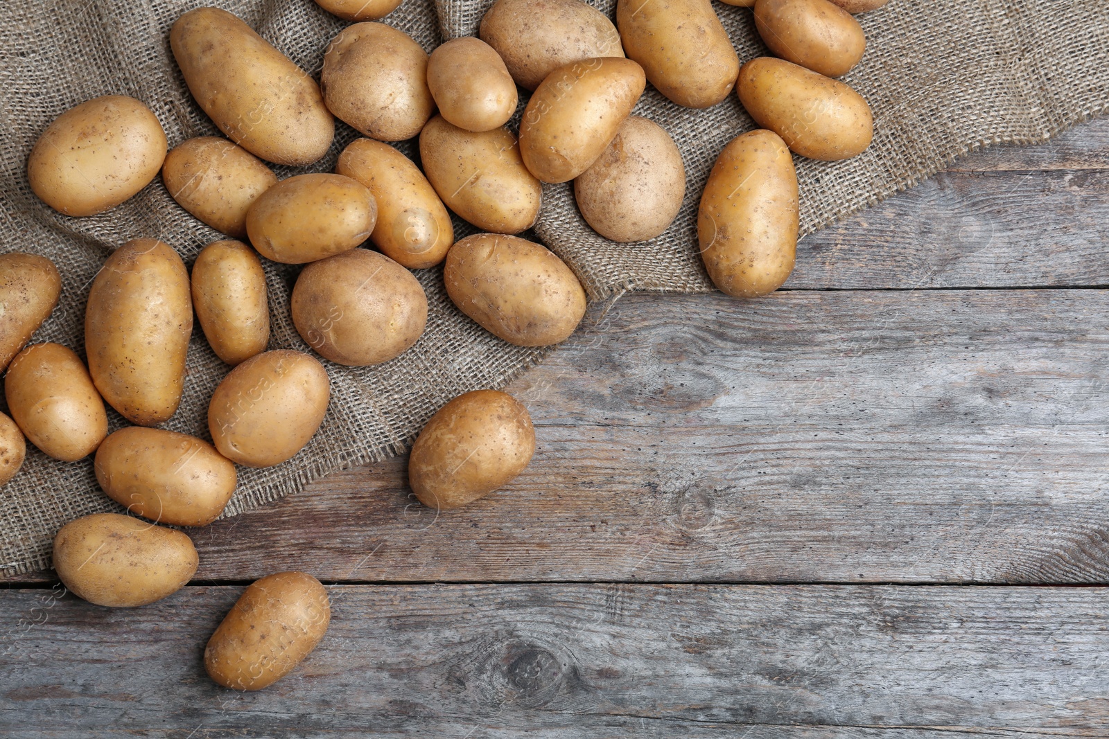 Photo of Fresh ripe organic potatoes on wooden background, top view