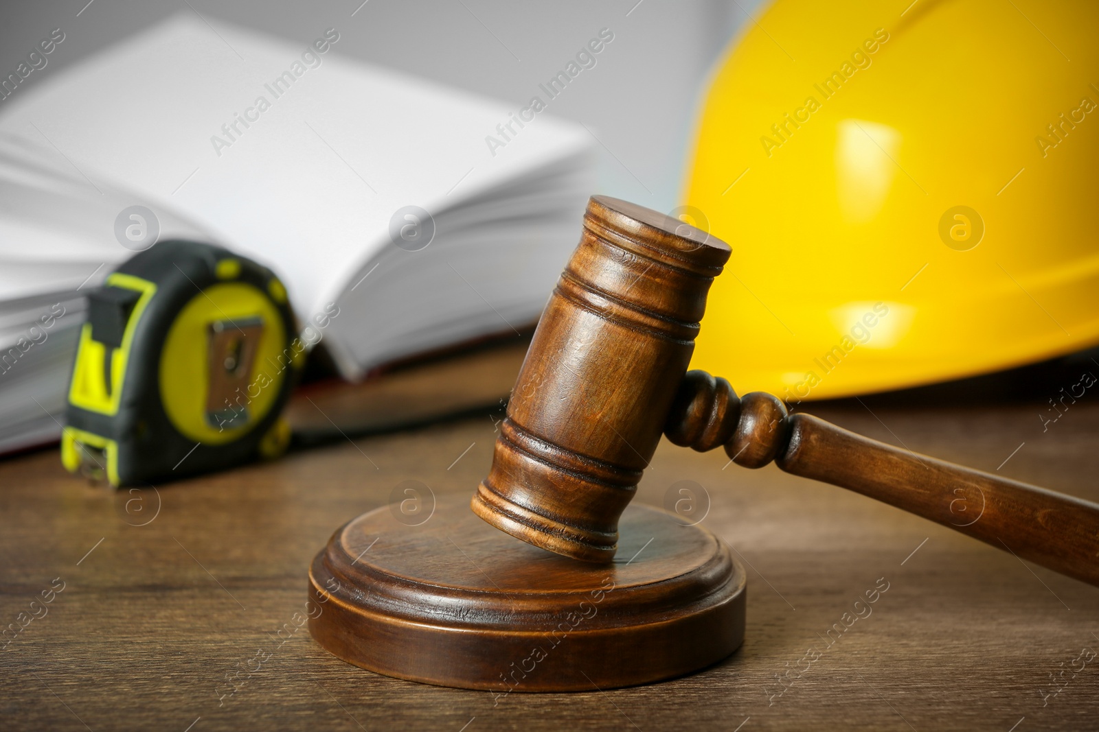 Photo of Construction and land law concepts. Judge gavel, open book, tape measure with protective helmet on wooden table, closeup