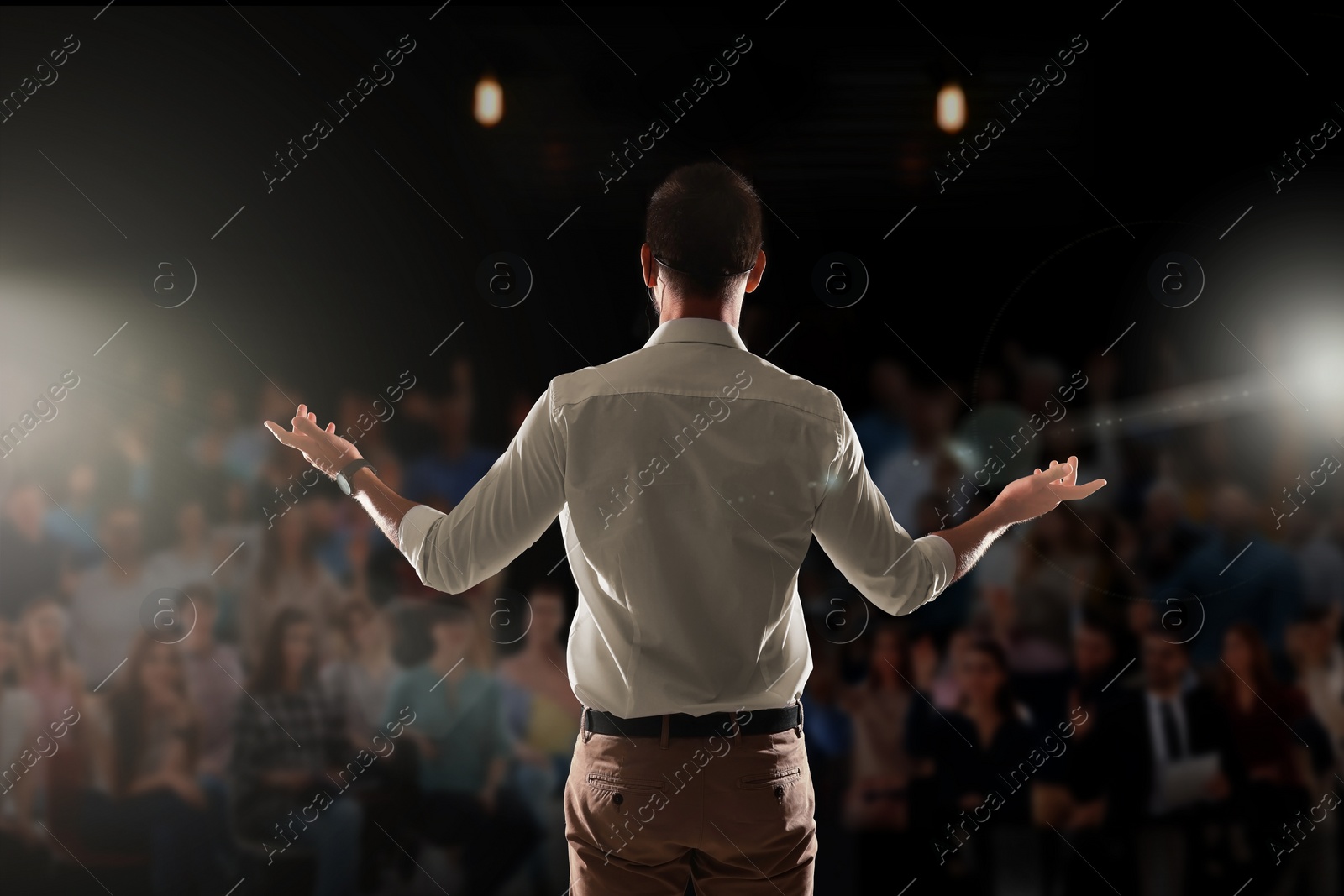 Image of Motivational speaker with headset performing on stage, back view