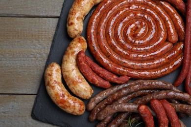 Photo of Different delicious sausages on wooden table, top view. Assortment of beer snacks