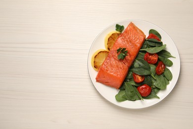 Photo of Tasty grilled salmon with basil, tomatoes and lemon on white wooden table, top view. Space for text