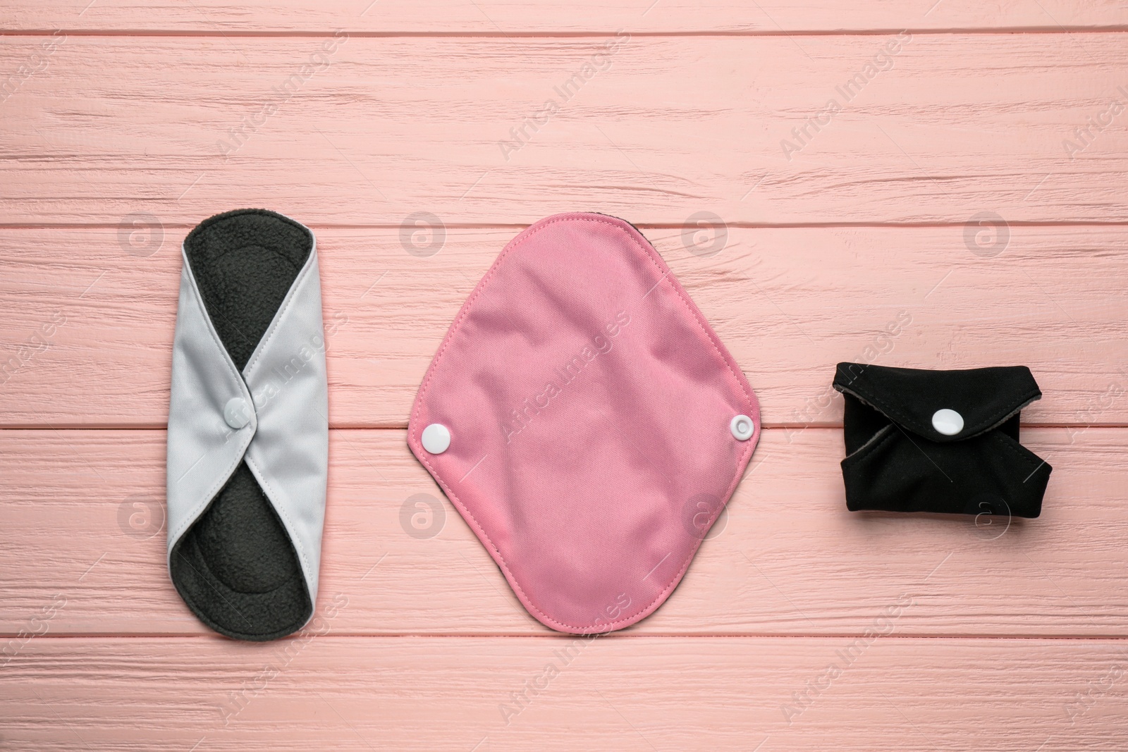 Photo of Many reusable cloth menstrual pads on pink wooden table, flat lay